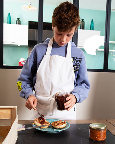 Recette de Noël : les burgers de fête de Kimi. Tartiner l’intérieur des pains avec la terrine. Ajouter de la confiture de figue.